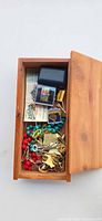 Open cedar box showing assorted jewelry, pins, beads, tickets