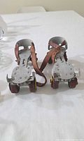 Front view of both adjustable metal roller skates showing frames, straps, wheels and wear