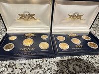 Both display cases opened showing 1999 and 2000 gold-plated coin sets