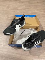 Top view of sneakers in box showing tags attached and tissue paper