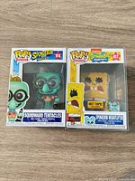 Front view of both boxed figures showing characters, numbers, Hot Topic sticker on Spongebob box, plastic protectors visible