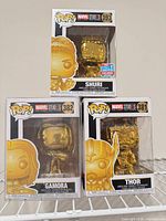 Front view of Shuri, Gamora, Thor gold chrome Funko Pop figures in boxes