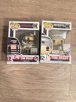Front view of both boxed Tom Brady Funko Pop! figures (#170 Buccaneers, #59 Patriots)