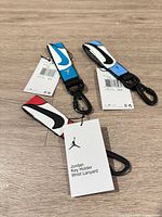 Front view of three Jordan wrist lanyards displaying colors and Swoosh graphic
