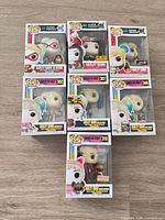 Seven boxed Harley Quinn Funko Pop figures laid out