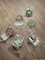 All six enamel pins in individual plastic bags, front view
