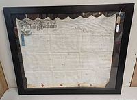 Full view of framed indenture document showing calligraphic header, scalloped top, wax seals