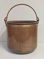 Front view of copper pot showing handle, patina and rolled rim