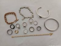 All bracelets and rings laid out on white background