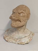 Front view of plaster grotesque head bust showing facial detail and base