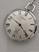 Front view of pocket watch showing dial, brand, date window
