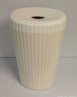 Front view of ribbed ivory plastic hamper with lid and central opening