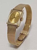 Overall angled view of gold Longines watch on mesh bracelet