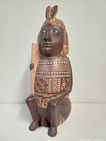 Front view of seated polychrome terracotta figure holding staff