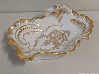 Top view of shell-shaped porcelain dish showing gold gilt rim and interior design