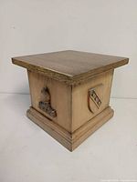 Oblique view showing front panel with horse-head crest relief and overall square form