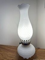Lamp illuminated showing hobnail glass and brass collar