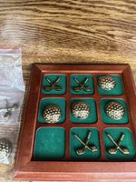 Board with brass golf ball and crossed club pieces in place