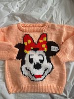 Front view of peach sweater displaying full Minnie Mouse graphic