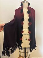Full view of shawl on dress form showing gradient color and pom poms