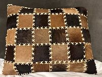 Front view of cowhide patchwork pillow showing full checkerboard design