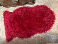 Full view of red faux fur rug on wood floor