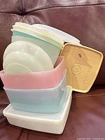 Stack of pastel rectangular containers, round bowls and square yellow lid