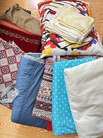 Multiple folded textiles including velvet cover, cushion, napkins and various fabric yardage