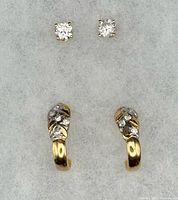 Both pairs of earrings laid out on grey felt showing design and diamonds