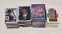 Stacks of assorted baseball trading cards with visible Topps Mark Grace card, Elvin (unknown) card and puzzle card bundle