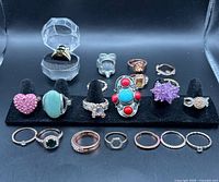 Front view of 18 assorted costume rings on display stand and tray