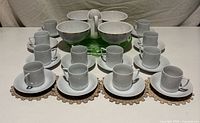 Full set of porcelain espresso cups, saucers, creamer, footed bowls displayed on green depression glass tray