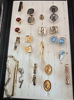 Overall view of cufflinks, tie tacks, tie bars and bracelet arranged on display board