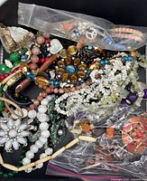 Box of assorted costume jewelry pieces showing variety and quantity