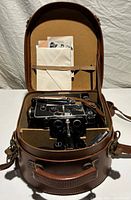 Camera, accessories and paperwork inside open leather case