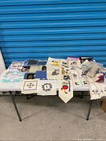 Overall view of table with finished cross-stitch pieces and fabric packs