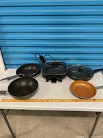 All cookware pieces on table against blue backdrop