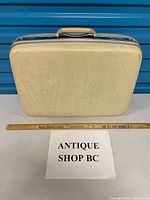 Front view of cream Samsonite hard-shell suitcase with ruler for scale