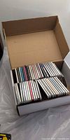 Open cardboard box filled with CDs in jewel cases