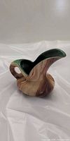 Front view of the marbled pottery creamer showing handle, spout, green interior