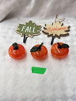 Full lot view: three glass pumpkins and two wooden maple-leaf signs