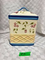 Front view of Pfaltzgraff Cherry Basket cookie jar showing cherry design, lattice band, blue trim