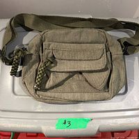 Front view of olive corduroy purse showing adjustable strap and exterior pockets