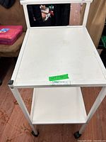 Full view of white two-shelf metal cart showing handle, shelves, and casters