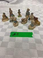 All ten Wade glazed ceramic figurines grouped on checked cloth