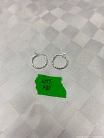 Pair of twisted silver hoop earrings placed on surface