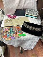 Overall lot layout showing eyeglass case, pouches, cosmetic bag, wallet, clutch