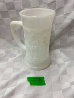 Full view of milk glass mug showing handle, flared rim, relief design