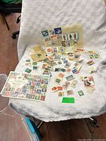 Wide view of entire lot showing loose stamps, partial envelope and glassine sleeve on white cloth