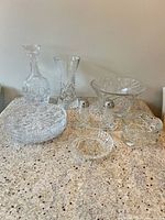Group shot showing decanter with stopper, tall vase, round platter, flared bowl, square bowl, small round dish, and pair of shakers